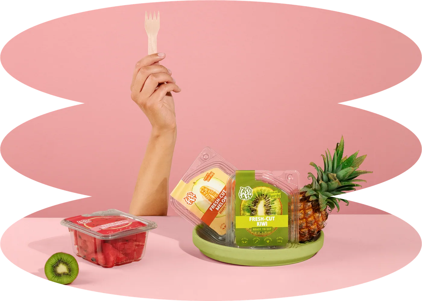 Ranka su mediniu šakute virš Taste it easy produktų rožiniame fone