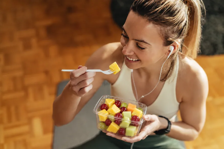 Sportuojanti moteris valgo vaisių mišinį